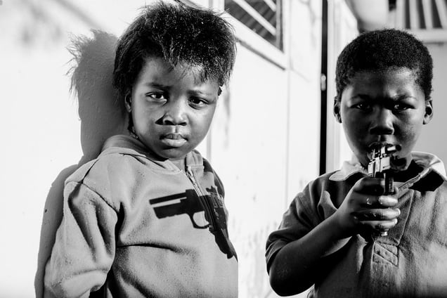 Two kids play with a pistol.