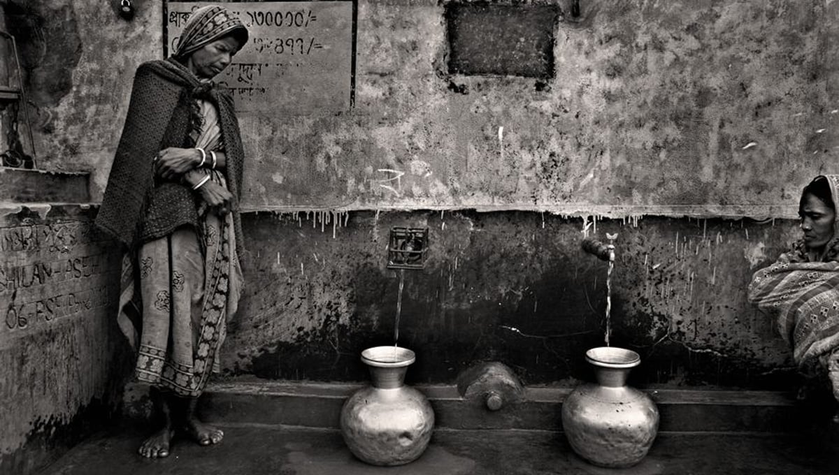 Sharoshoti Munda and Rubala Munda are waiting for their pitchers to be filled with water from the only filters in the area. They had to stand in a queue for hours like hundreds of others. Patrakhola, Satkhira. © Munem Wasif/VU'