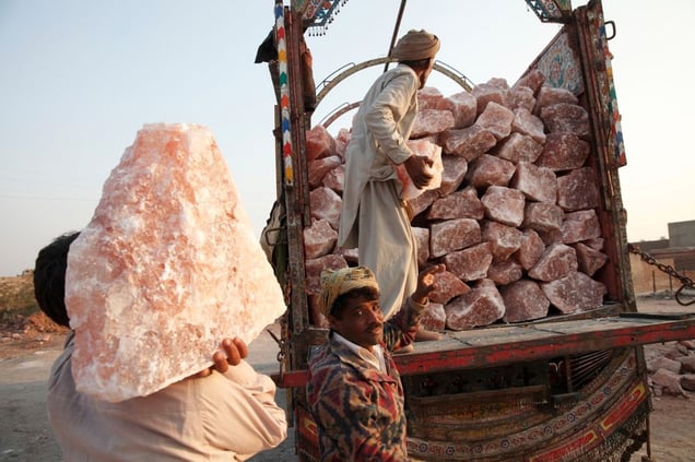 Men load large chunks of pink rock salt on to trucks at a salt distribution area next to Khewra Salt mine.