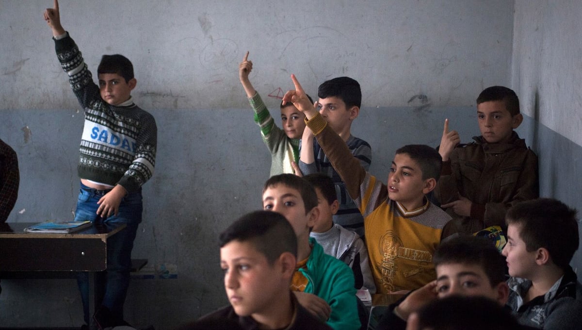 15/11/14. Alqosh, Iraq. Wassam (centre right, yellow shirt) raises his hand to answer a question at the Alqosh School. Three of the children from the orphanage currently study at the school, which was founded in 1926.