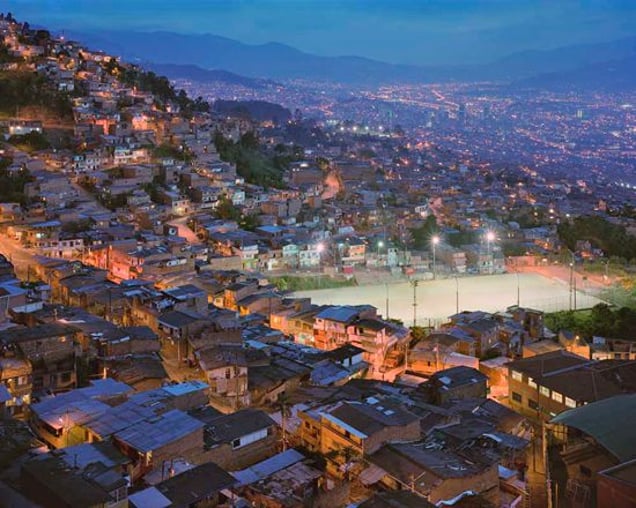 The Granizal district of Medellin, Colombia, first populated by refugees (IDPs) 30 years ago. The football pitch was previously the camp’s refuse patch and can’t be built on due to the danger of subsidence. From "Forensic Traces of War" © Simon Norfolk