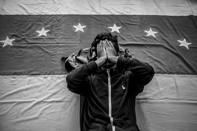 Caracas, Venezuela, February 20, 2015. A protestor lying on the Venezuelan flag at a demonstration calling for the release of the Mayor of Caracas, Antonio Ledezma. © Alejandro Cegarra / Getty Images Reportage