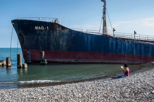 Georgia, Sukhumi, Abkhazia A woman looks into a mirror as she sits on the beach next to the Black Sea. Behind her lies the wreck of a Tanzanian ship that was stranded on the shore during a storm in 2007.© Petrut Calinescu