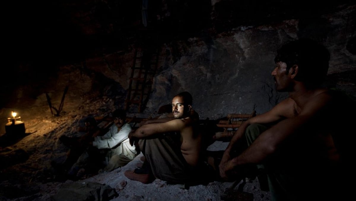 Salt miners take a rest inside the darkness of the Khewra salt mine.