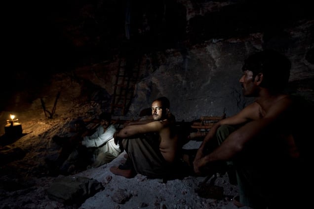Salt miners take a rest inside the darkness of the Khewra salt mine.