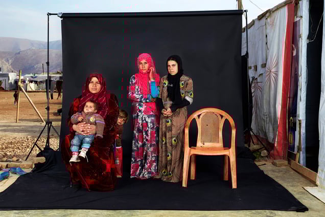 Portrait of a Syrian refugee family in a camp in Bekaa Valley, Lebanon, on 15 December 2015. The empty chair in the photograph represents a family member who has either died in the war or whose whereabouts are unknown.