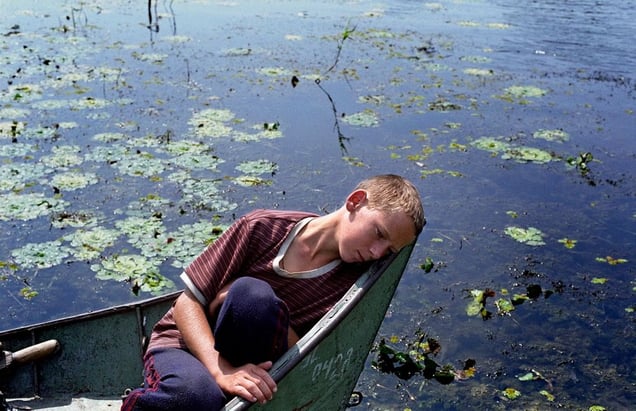 Romania, Tulcea, Danube Delta12-year-old Vanea rests in the prow of a fishing boat. He left school to work for a fisherman in the village of Sfistofca. The inhabitants of the Danube Delta live an isolated existance and make a living mainly by fishing and farming. The region's well-preserved delta eco-system was declared a UNESCO World Heritage Site in 1991.© Petrut Calinescu