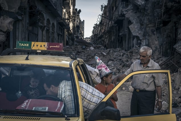 Khalidiya district, Homs, Syria, Sunday June 15, 2014. Abu Hisham Abdel Karim and his family load their belongings into a taxi. Taxis incongruously drive along deserted streets in ruins, bringing families to inspect what remains of their homes. © Sergey Ponomarev for The New York Times