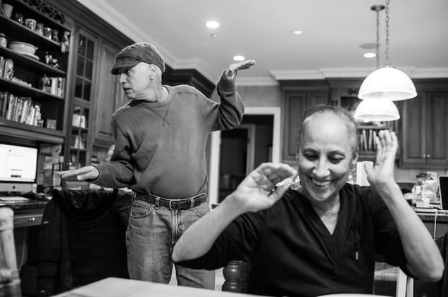 In his kitchen, Howie Borowick breaks into a bouncing dance to hopefully get a smile out of wife, Laurel. Chappaqua, New York. February, 2013 © Nancy Borowick