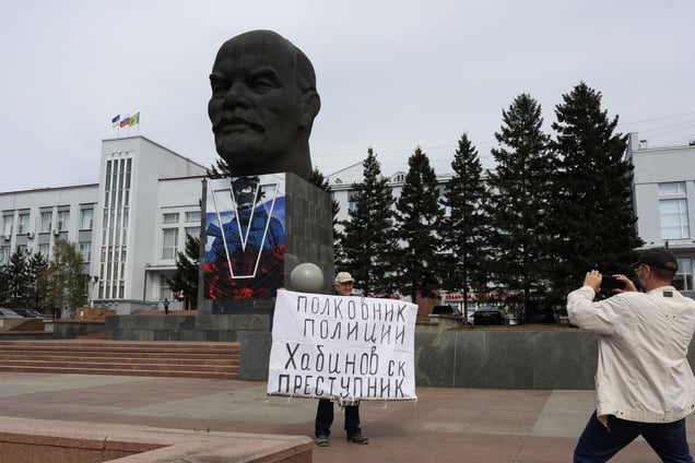 A man holding a protest sign poses in front of the world’s largest Lenin head statue at Lenin Square in Ulan-Ude, Republic of Buryatia on May 15, 2024.