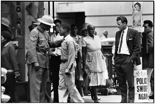 Police "swoop." During a swoop, police are everywhere, checking individuals' passes. A young boy is stopped and asked for his pass as a white plainclothesman looks on.