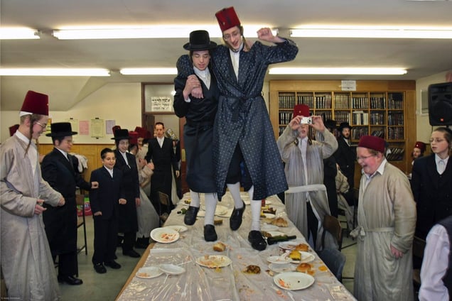 During the Jewish festival of Purim a group of Orthodox Jewish boys from the Viznitz Yeshiva (school) in fancy dress celebrate the festival with a feast. The evening quickly moves onto dancing on the tables that sends food flying everywhere. The school boys drink large amounts of alcohol throughout the day and night.