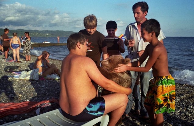 Georgia, Sukhumi, Abkhazia A tourist holds onto a bear which is being led by a hawker who offers tourists the opportunity to have their picture taken with the bear. Children pet the bear enthusiastically.© Petrut Calinescu