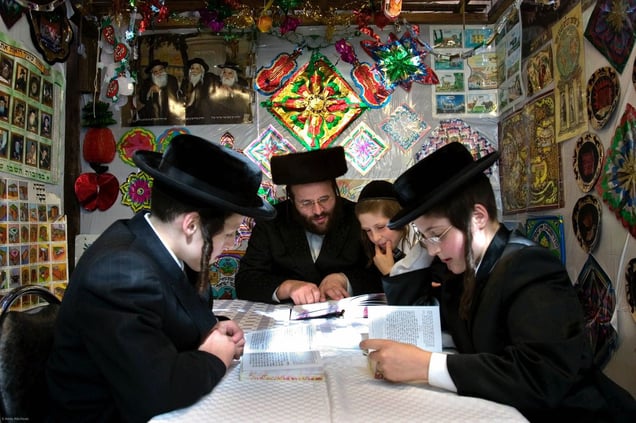 Mr Leibowitz and his 3 sons reading (learning) the Torah inside their sukkah during Sukkot, the feast of Tabernacles. The holiday commemorates the forty-year period during which the children of Israel were wandering in the desert. In honor of the children of Israel in the wilderness, men dwell in temporary shelters.