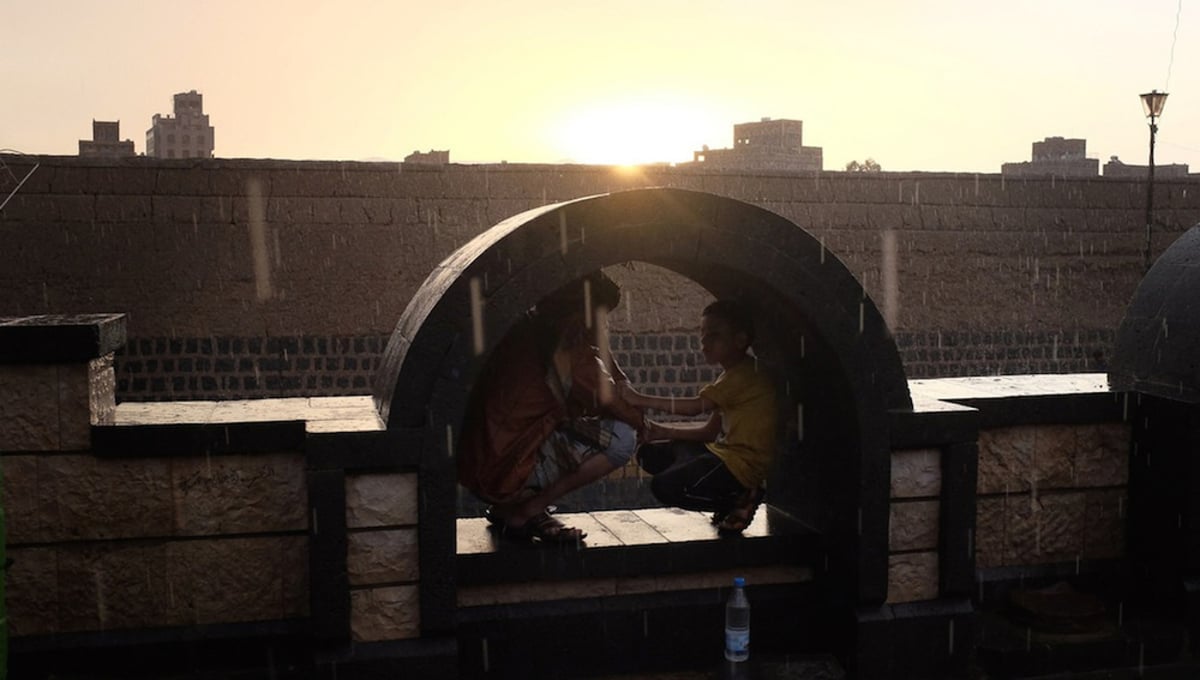 Yemeni boys sit together in a public plaza during a sunset rain on August 6, 2015 in Sana'a, Yemen. © Alex Potter