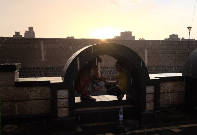 Yemeni boys sit together in a public plaza during a sunset rain on August 6, 2015 in Sana'a, Yemen. © Alex Potter