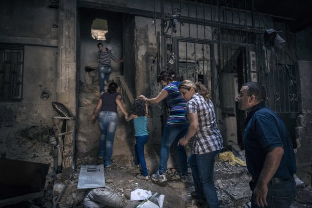 Homs, Syria, Saturday June 14, 2014. A family walking through the rubble on the way to their apartment abandoned two years earlier, to see whether it is habitable. © Sergey Ponomarev for The New York Times