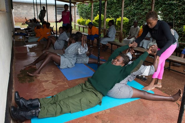 Margareth Njeri (23) helps a guard and a prisoner to stretch during a Yoga class in Langata Women Prison.