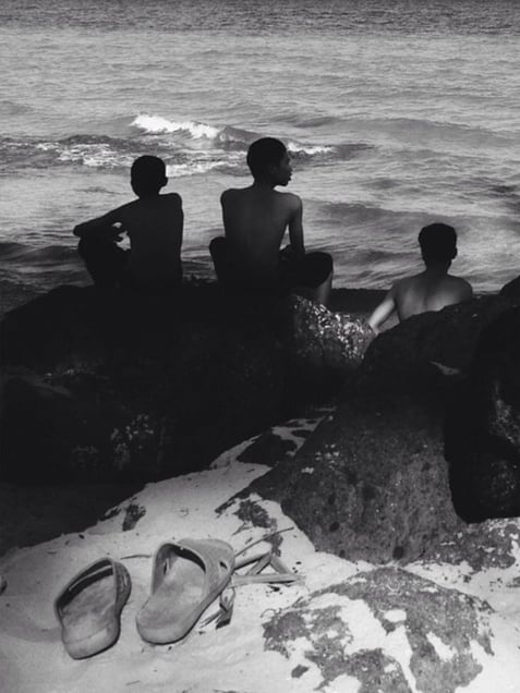 three men are sitting by the sea