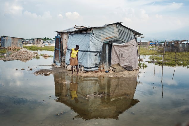 A woman standing next to her house in the flooded landscape at Rapatriès.