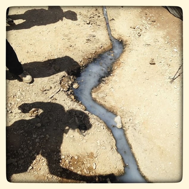 The boys take photos by a waste water stream