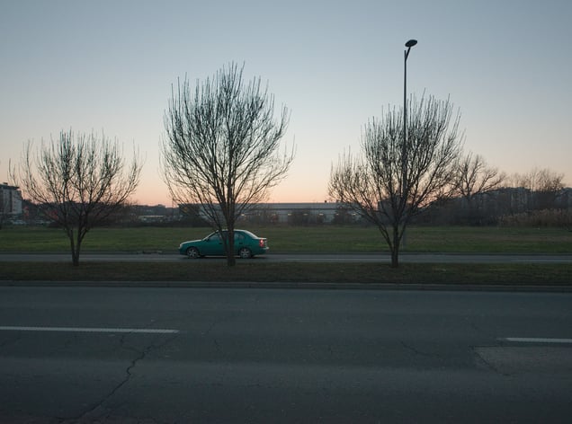 The edge of a residential quarter. A broad road and an open vacant area separate the housing blocks from the supermarket visible in the distance.