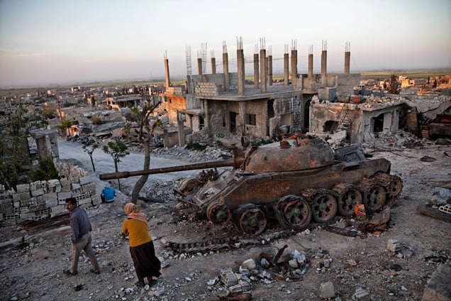 Kurdish couple walks by a destroyed tank in the rubble in the destroyed town of Kobane, Syria, on 18 April, 2015.