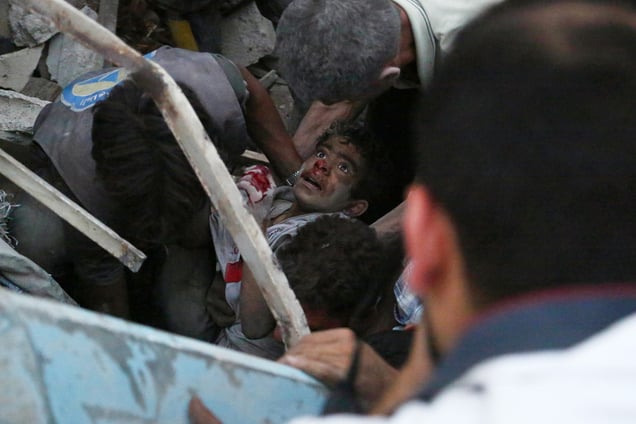 A boy is evacuated from rubble following reported airstrikes in the city of Douma, Syria, 16 June 2015.