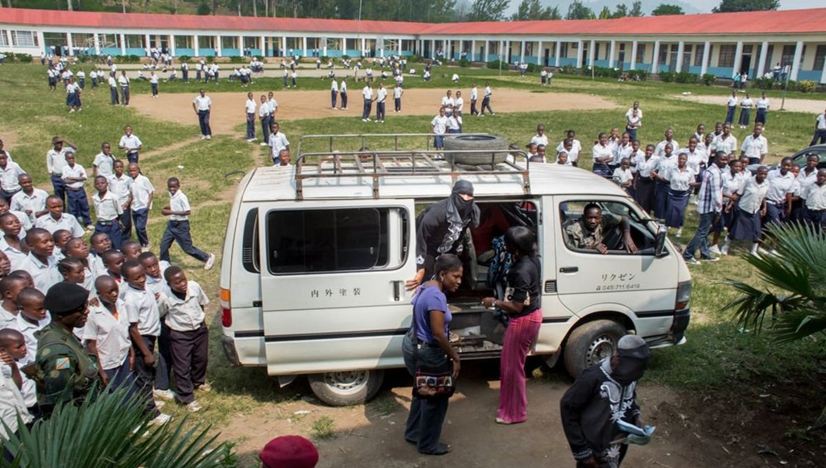 Students flock around a van delivering women scheduled to testify in a makeshift courtroom set up in the auditorium of a Catholic school in Minova.  Victims could not afford a trip to Goma, more than 30 miles away, so the court went to them in Minova. © Diana Zeyneb Alhindawi