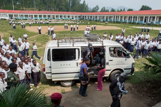Students flock around a van delivering women scheduled to testify in a makeshift courtroom set up in the auditorium of a Catholic school in Minova.  Victims could not afford a trip to Goma, more than 30 miles away, so the court went to them in Minova. © Diana Zeyneb Alhindawi