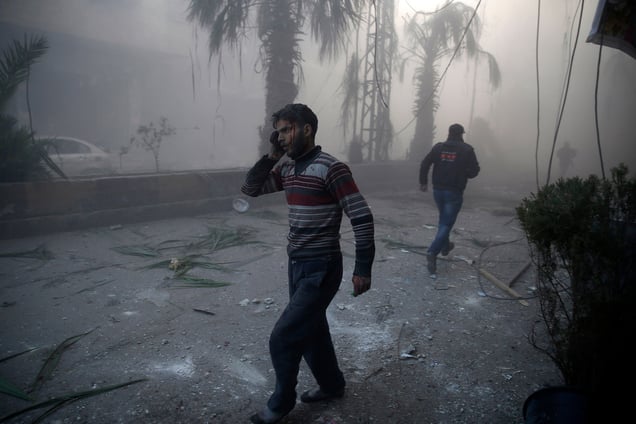 A wounded man walks out of a dust cloud following reported airstrikes in the town of Hamouria, Syria, 09 December 2015.