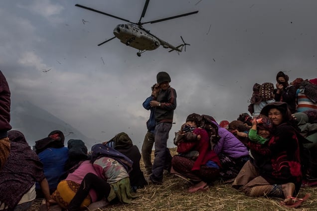 Nepalese villages watch a helicopter picking up a medical team, dropping aid atthe edge of a makeshift landing zone in Gumda, Nepal, 09 May 2015.
