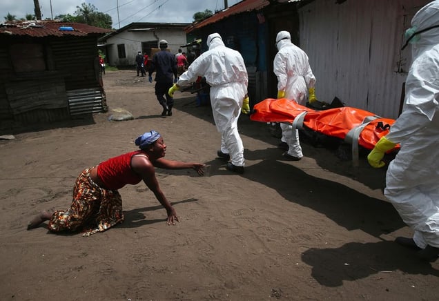 Sister's Grief. A woman crawls towards the body of her sister as Ebola burial team members take her away. From the series "Ebola Crisis Overwhelms Liberian Capital." Winner of L’Iris d’Or, 2015 Sony World Photography Awards.