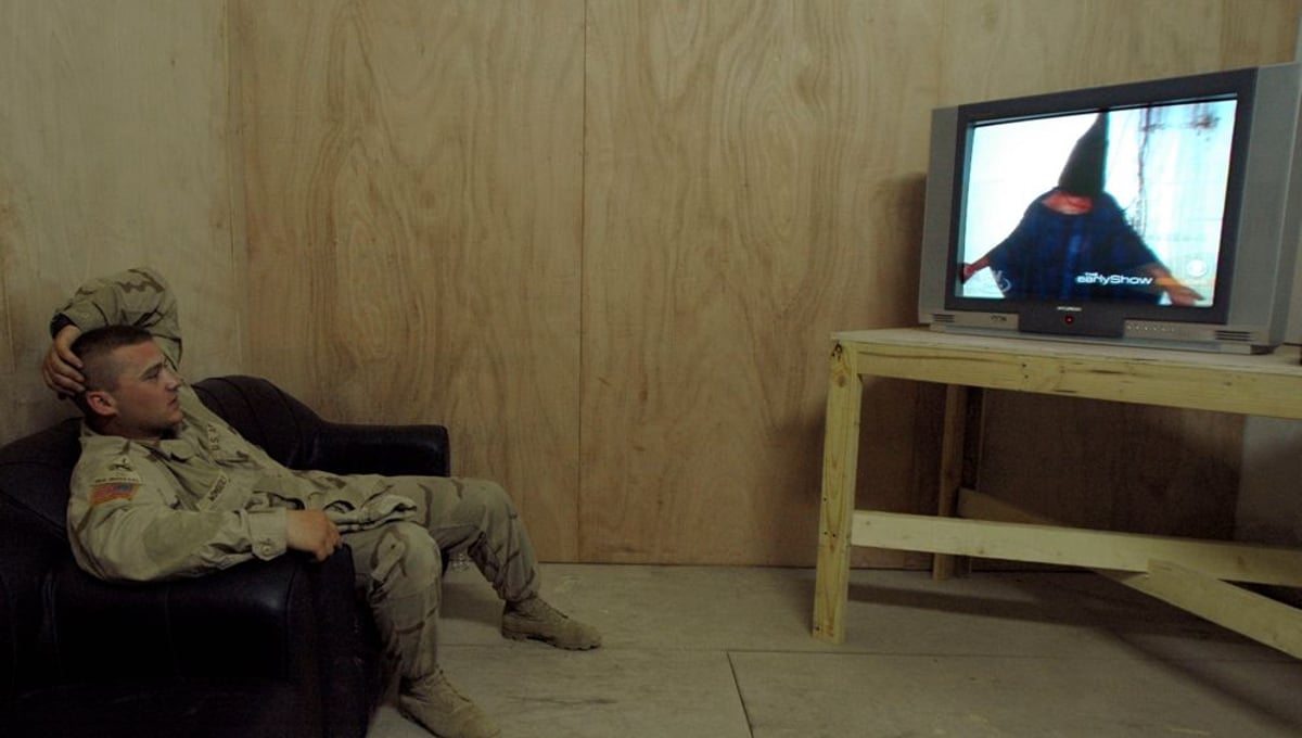 Specialist William Wimberly watches George W. Bush apologize on behalf of the US military for the torture that took place at Abu Ghraib prison. © Ashley Gilbertson