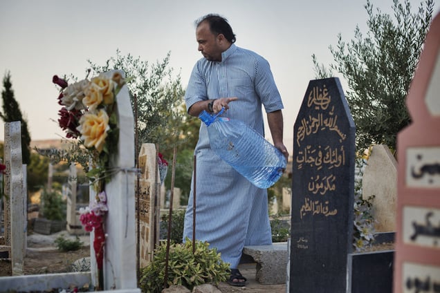 Jaser, from Falluja, washes his father's grave in the new part of Shaqlawa's graveyard. His father died two months after arriving to Shaqlawa as a displaced person, early 2014. 28/08/15. Shaqlawa, Iraq.