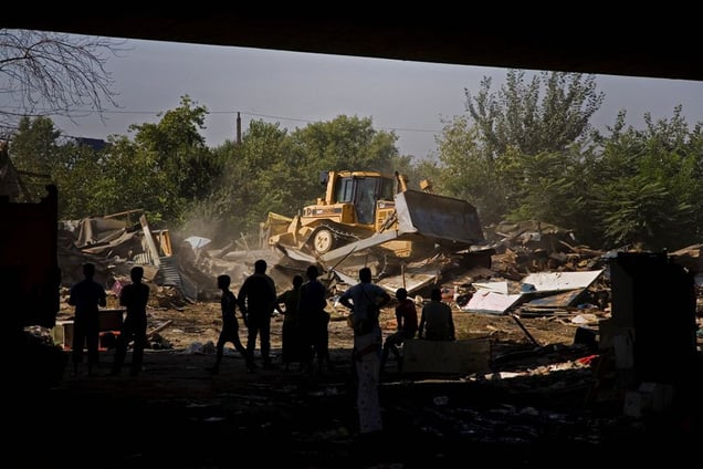 Bulldozers flatten homes in the Nova Gazela settlement while families, social workers and police watch from under the Gazela bridge. © Matt Lutton