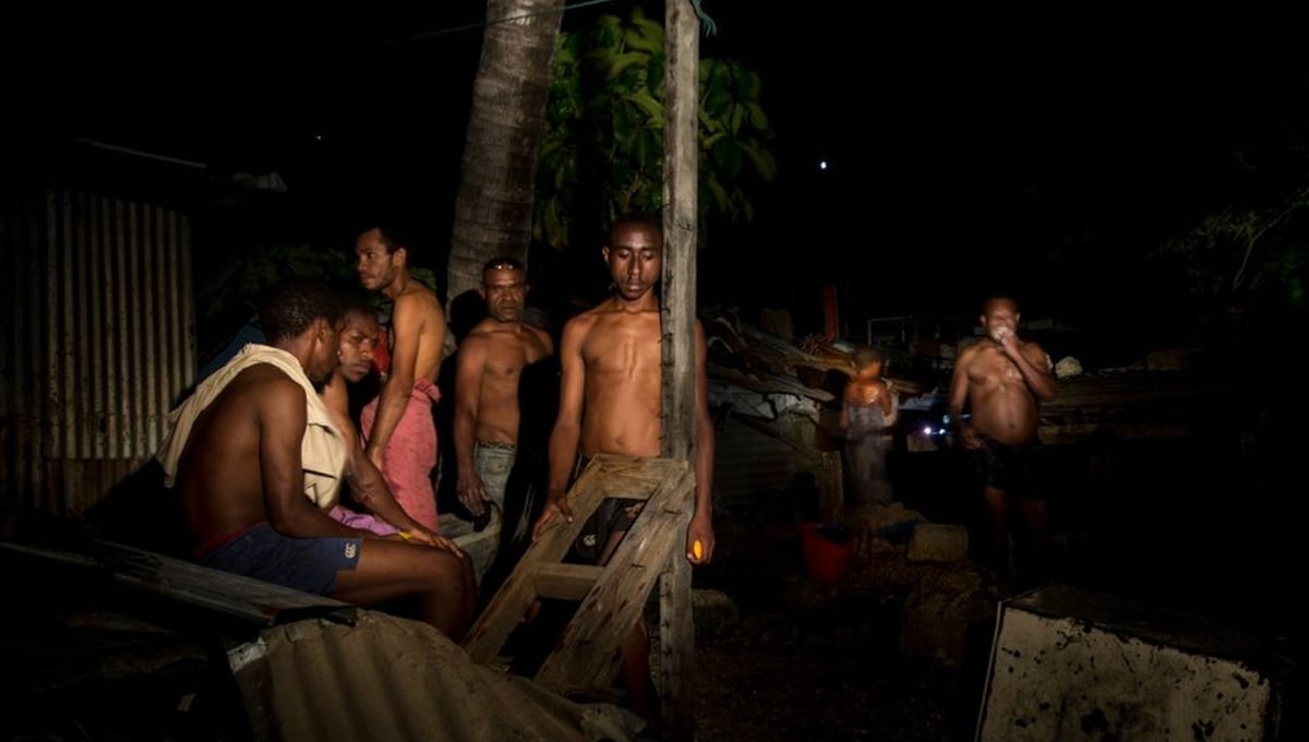 A group of men are washing from a hose connected to a broken water pipe.  When 21 houses at Paga Hill were demolished, all water and electricity supplies to the community were damaged.