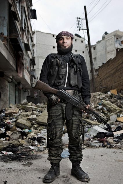 An FSA fighter stands with his rifle on a street damaged by fighting in the Shaar district of Aleppo, February 7, 2013.  © Nish Nalbandian