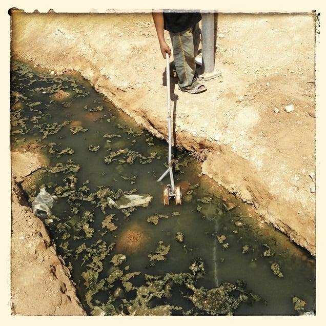 A child with rubbish in the waste water running through Za'atari refugee camp
