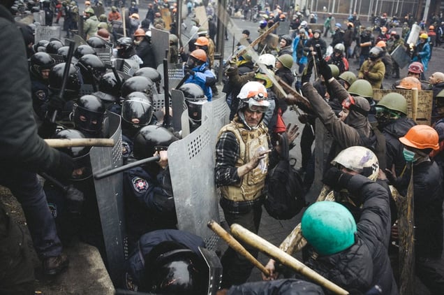Volunteer of the Red Cross tries to stop protesters and do not to let them to beat the police.  Kiev, Feb. 20, 2014