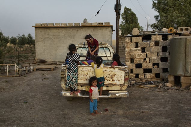 A group of displaced children play on the back of a pick up truck at the chicken farm of Dibaga. 47 families, 260 people, girls, boys, men and women from Jarallah now live together in one building. 04/07/2015.
