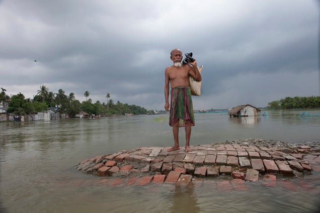 A flood affected man stands on a highland, waits for a boat.