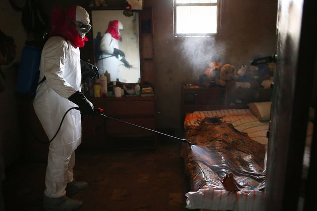 Bedroom. A burial team sprays disinfectant over the body of a woman suspected of dying of Ebola in her home. From the series "Ebola Crisis Overwhelms Liberian Capital." Winner of L’Iris d’Or, 2015 Sony World Photography Awards.