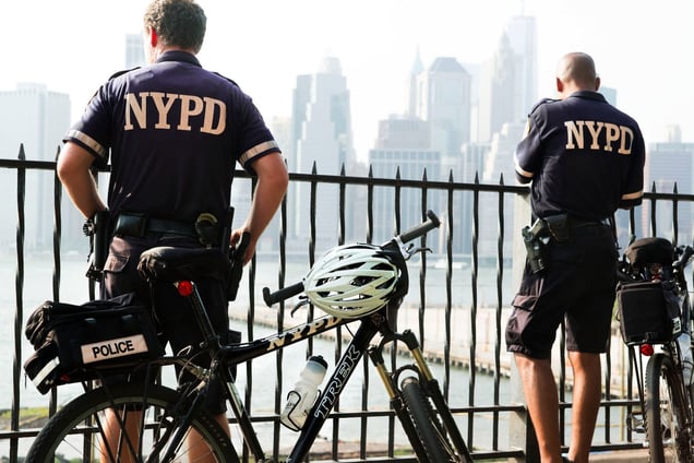 Bicycle police, bank East River, Manhattan behind.