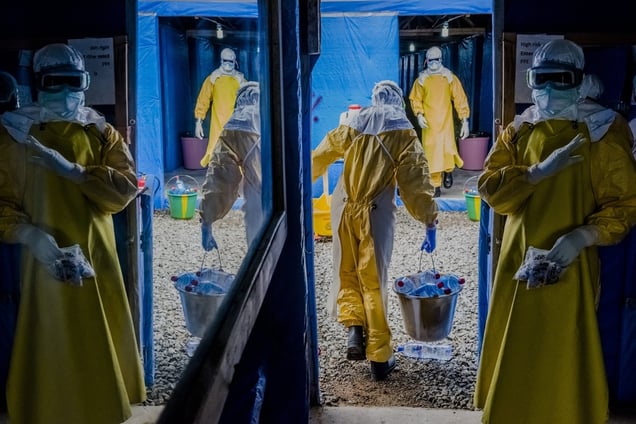 Bong County Ebola Treatment Unit, Suakoko, Liberia, October 7, 2014. Health workers entering the high-risk zone to do their morning rounds, removing waste from the previous night. Then a second team enters, with medical staff and health workers bringing food and water, doing blood tests, checking patients and providing medical care. © Daniel Berehulak / Getty Images Reportage / The New York Times