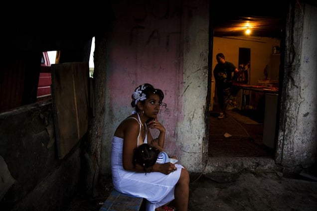 A mother breast-feeding her daughter outside of one of the few permenant homes during the celebration for a baptism in Nova Gazela. © Matt Lutton