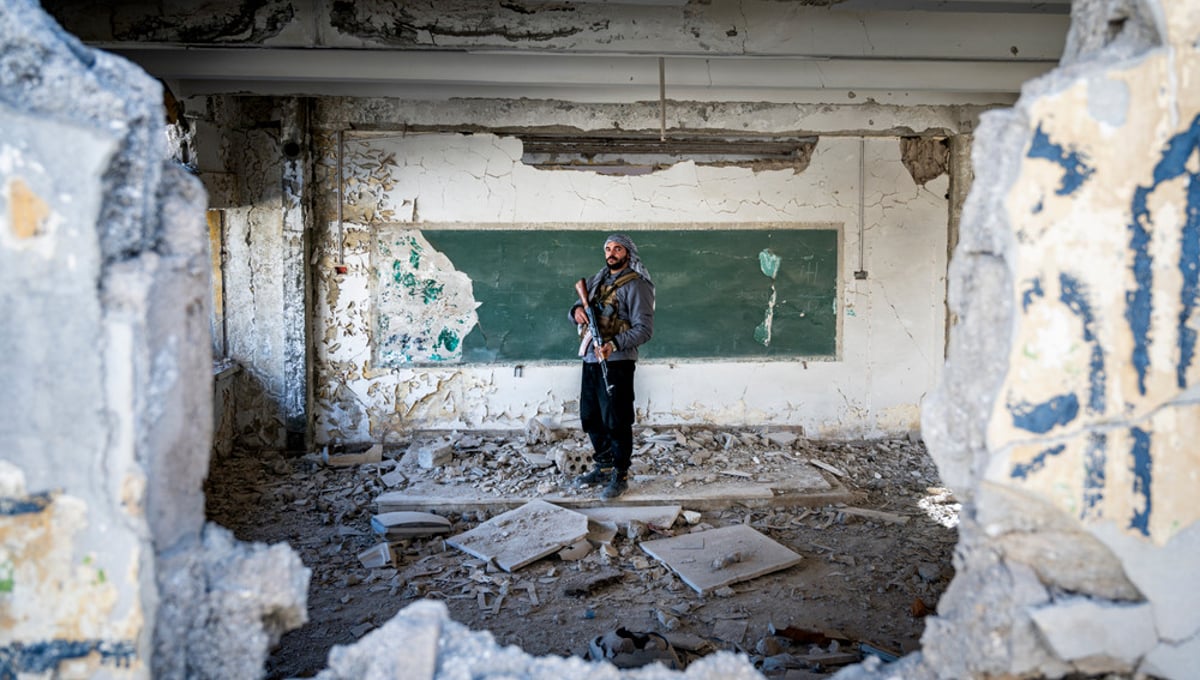 Jobar, Damas, Syrie.
Dans une école détruite par la guerre, un ancien élève devenu combattant pose là où il apprenait autrefois à lire et écrire.