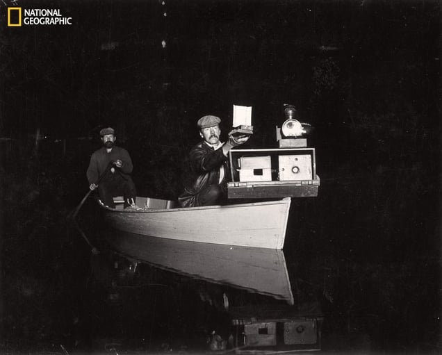 Photography pioneer Shiras made the first nighttime wildlife photos. Here he demonstrates his revolving camera tray, mounted jacklight, and handheld flashgun. From the October 125th anniversary issue of National Geographic magazine © George Shiras/National Geographic