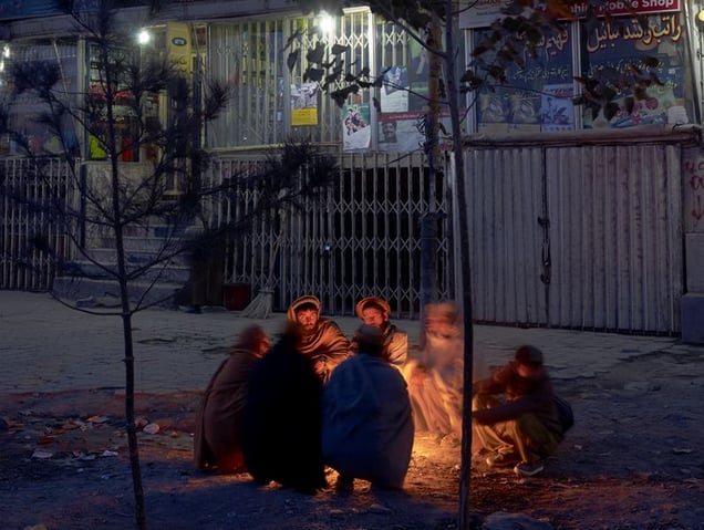 Before dawn, construction workers warm themselves over burning plastic and cardboard before beginning the job of attempting to get hired for a days work.
© Simon Norfolk.