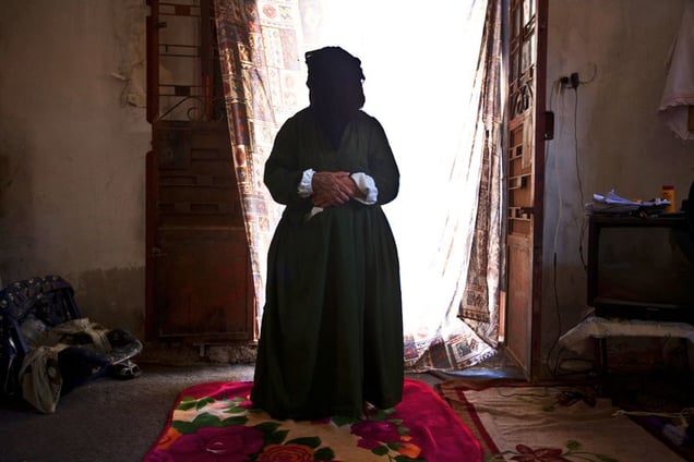 Jdeideh, Lebanon. Husniyah, 80 years old, comes from the village of Nazarieh. She arrived alone, three months ago, and she is now hosted in a small two-room-house together with seven other members of her family. Without money, they are helped by some neighbors who donated blankets and some food. © Matilde Gattoni